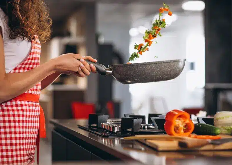 Pratos típicos do Guarujá: conheça algumas das delícias da cidade! Mulher cozinhando vegetais - Hotel Doral Guarujá